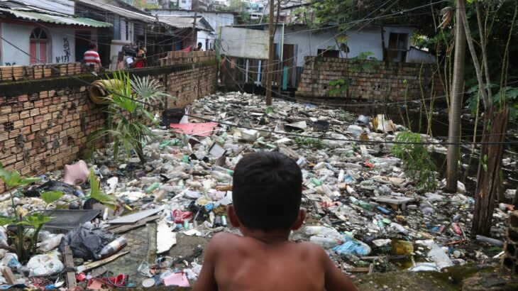 Criança em meio ao lixo trazido pela subida do rio Negro, na comunidade indígena Edite da Silva Kokama (Ricardo Oliveira/Revista Cenarium) 