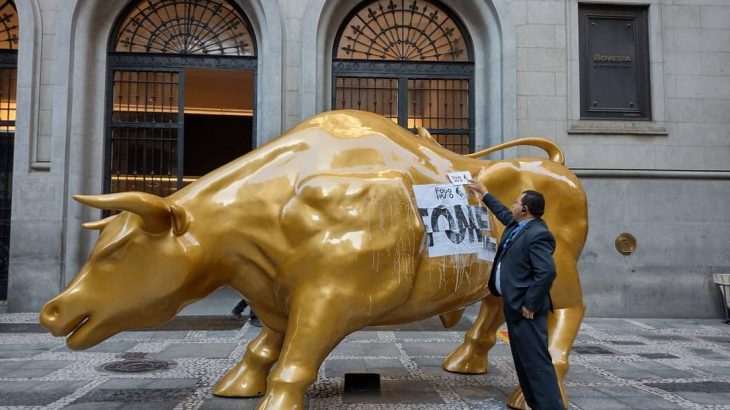 Estátua do touro dourado amanhece com adesivo de protesto contra a fome no lombo (Reprodução)