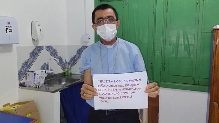 Bispo de Itacoatiara, Dom José Ionilton segura um cartaz pedindo para que a população não acredite em quem nega e tenta atrapalhar a vacinação contra a Covid-19 (Reprodução)