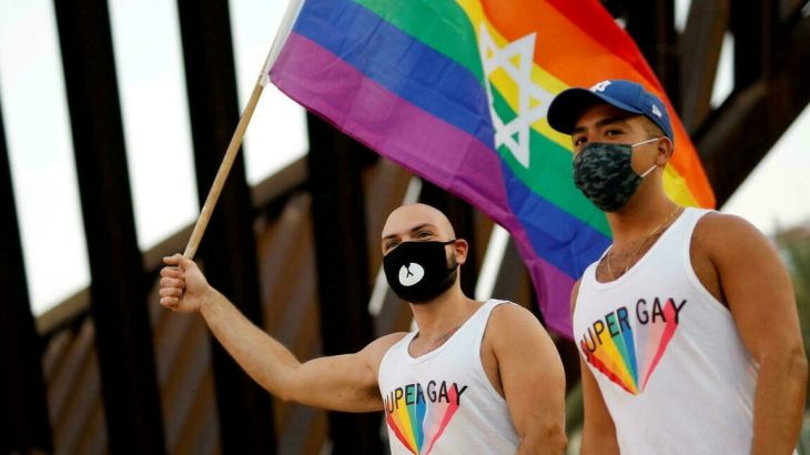 Casal gay carregando bandeira LGBTQIA+ (Reprodução/ Internet)