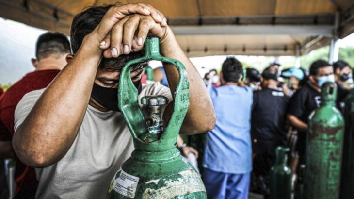 Cansado, familiar se debruça sobre um cilindro de oxigênio e aguarda para abastecer em usina de Manaus. (Bruno Kelly/ Reuters)