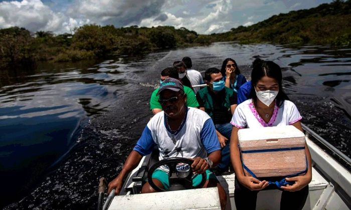 Profissionais de saúde levam, em um barco, doses da vacina Astrazeneca para aplicar na população das comunidades da calha do Rio Negro, zona rural de Iranduba, no Amazonas (Raphael Alves / Agência O Globo/15-04-2021)