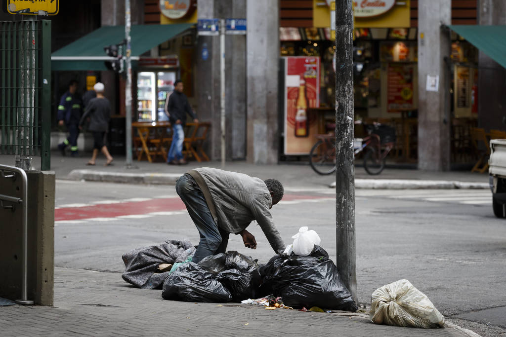 Pessoa em situação de rua revira sacos de lixo no Largo Santa Cecília, região central de São Paulo (Rubens Cavallari/20.out.22/Folhapress)