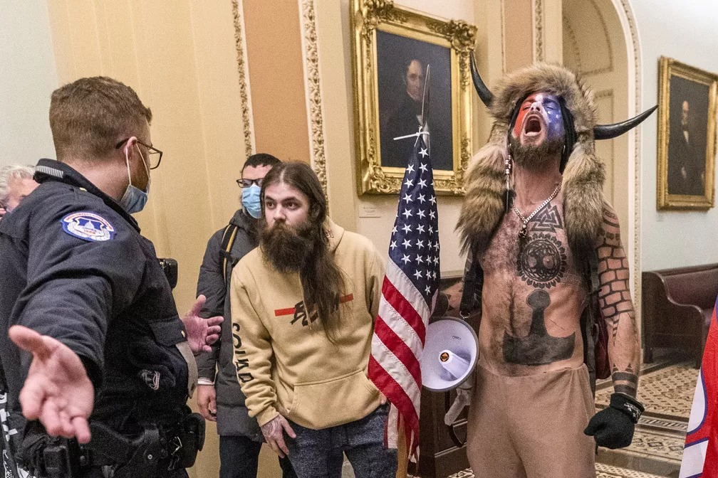 Foto de 6 de janeiro de 2021, dia da invasão ao Capitólio dos EUA, mostra policiais conversando com apoiadores do então presidente americano, Donald Trump, incluindo Jacob Chansley (à direita), do lado de fora do plenário do Senado —(Foto: Manuel Balce Ceneta/AP)