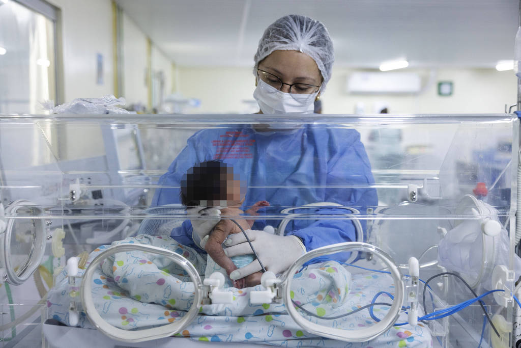 A fisioterapeuta Manoella Dias Barbosa cuida de um bebê Yanomami recém-nascido na UTI do Hospital Materno Infantil, em Boa Vista (Lalo de Almeida/Folhapress)