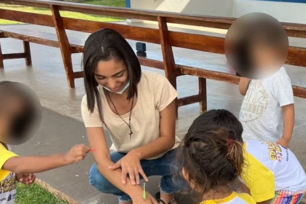 Giulyane Santana com alunos em escola.