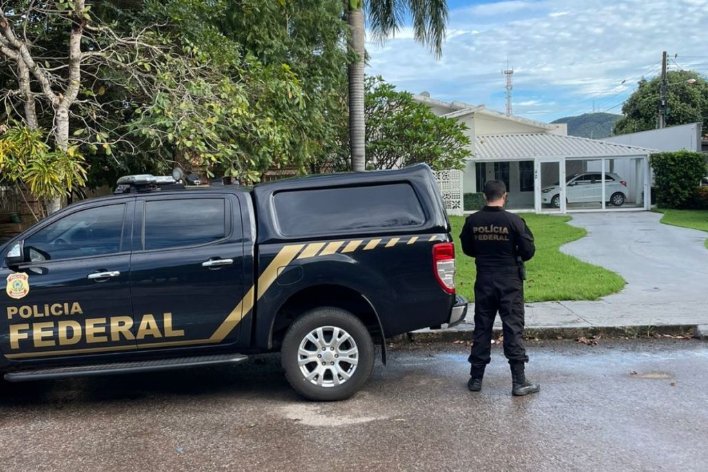 Imagem colorida mostra PF em frente a casa de suspeito. (Divulgação)