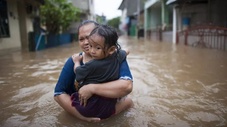 Mulher e criança caminham pelas águas da enchente no leste de Jacarta, Indonésia (Unicef)