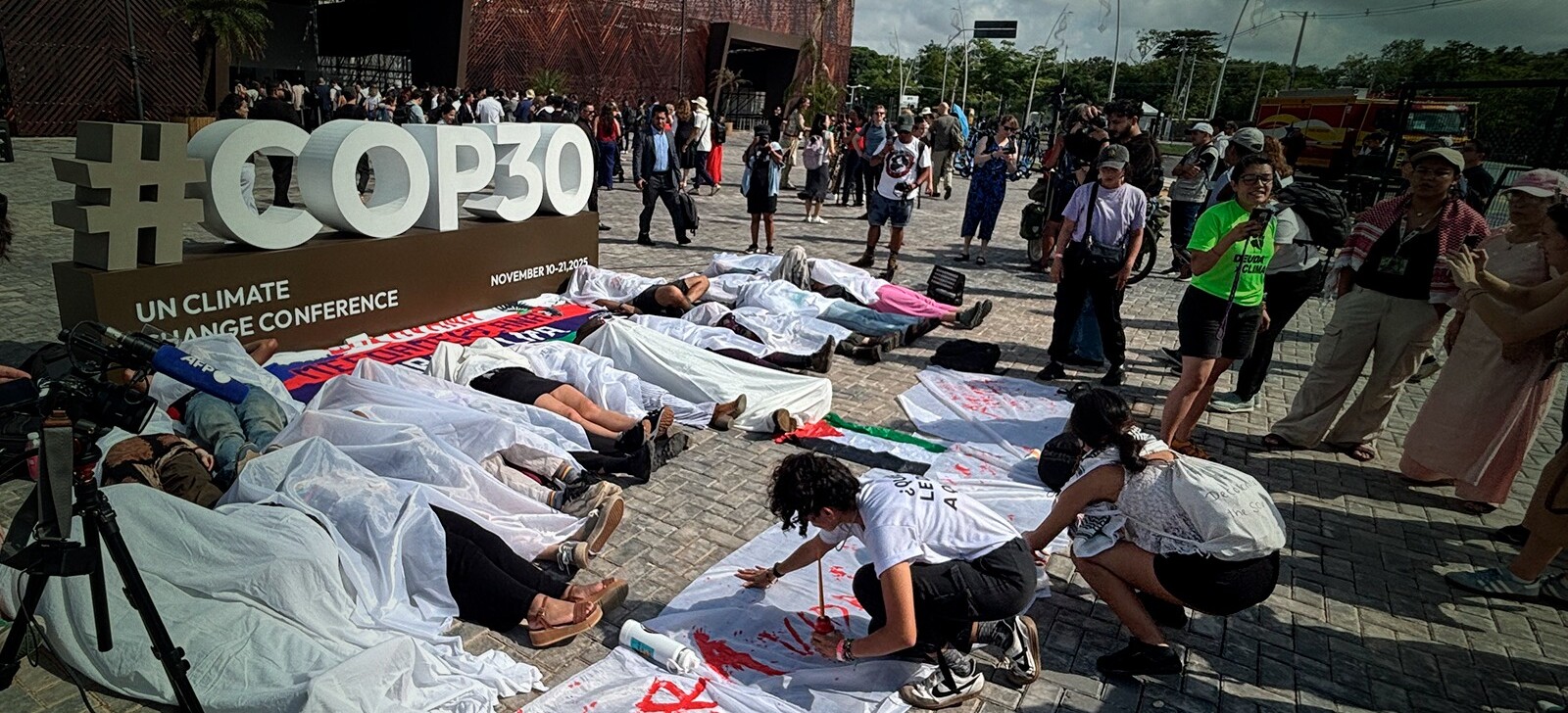 Ativistas simulam corpos em frente à Zona Azul da COP30 em ato contra desigualdade climática