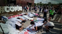 Ativistas simulam corpos em frente à Zona Azul da COP30 em ato contra desigualdade climática
